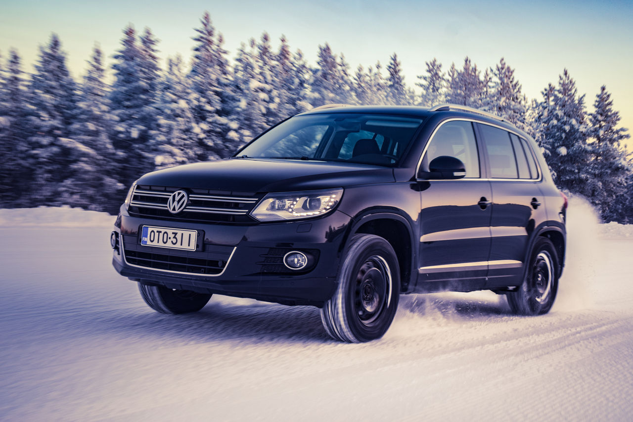 Nokia, Finland - February 2, 2018: Black SUV Volkswagen Tiguan accelerates on a flat snow surface in Lapland during a sunny day. Naturally blurred winter forest background. Color toning applied.