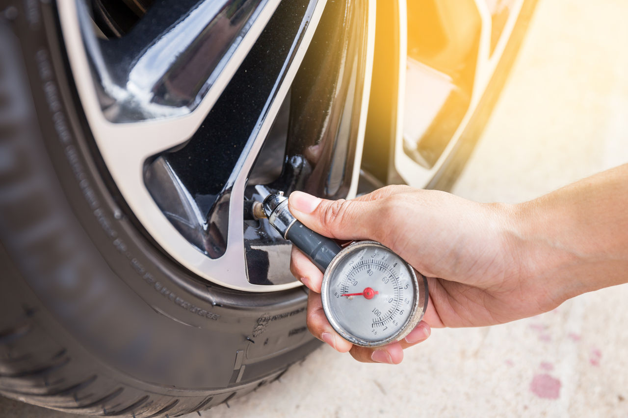Uniroyal - Close-Up Of Hand holding pressure gauge for car tyre pressure measurement